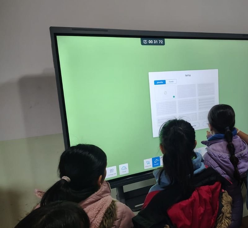 Alumnas de espaldas tocan una pantalla inteligente para elegir la plantilla de una actividad